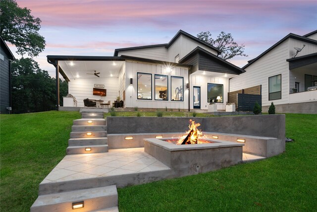 back of house at dusk featuring an outdoor fire pit, a yard, and a patio