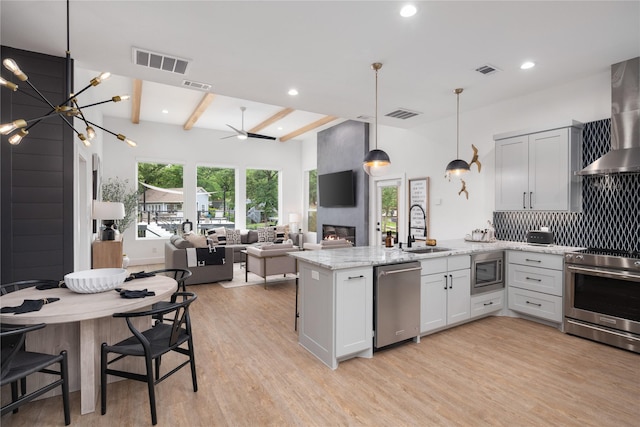kitchen featuring a sink, a peninsula, visible vents, light wood-style flooring, and appliances with stainless steel finishes