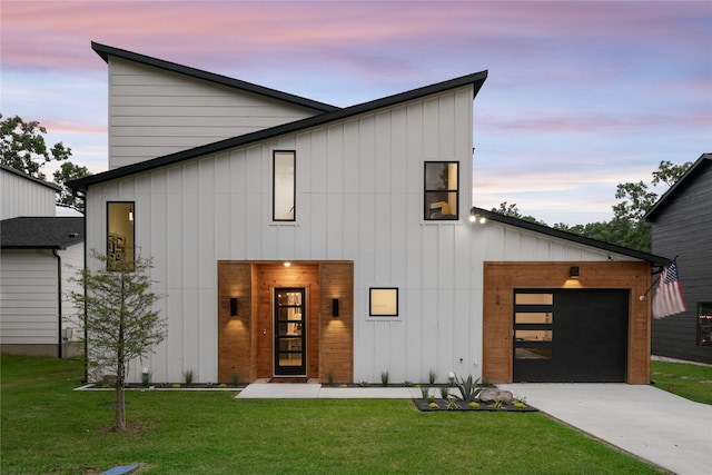 view of front of house with an attached garage, board and batten siding, a yard, and driveway