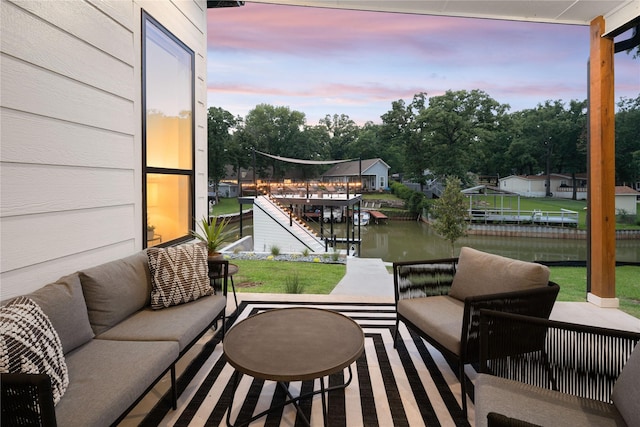 patio terrace at dusk featuring a water view and an outdoor living space
