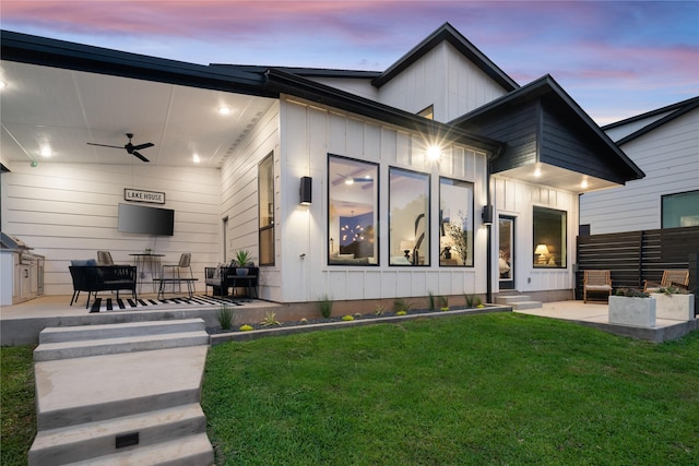 view of front of home featuring a ceiling fan, a patio area, a yard, and board and batten siding
