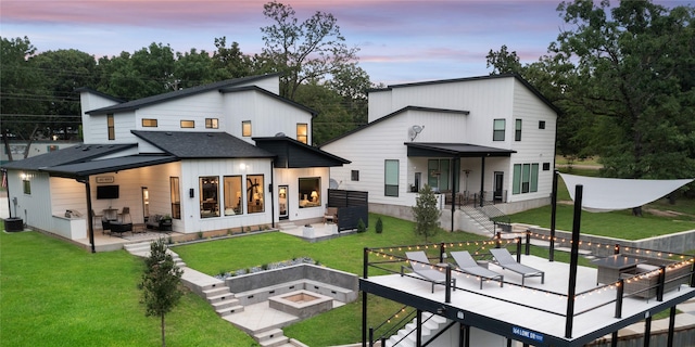 back of house with an outdoor living space with a fire pit, stairs, a patio area, and a lawn