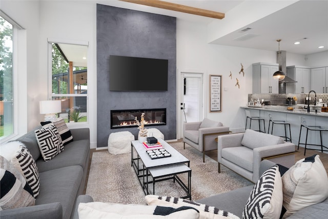 living area featuring beamed ceiling, recessed lighting, and a large fireplace