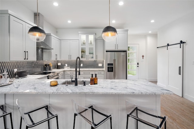 kitchen featuring a sink, a peninsula, a barn door, backsplash, and appliances with stainless steel finishes
