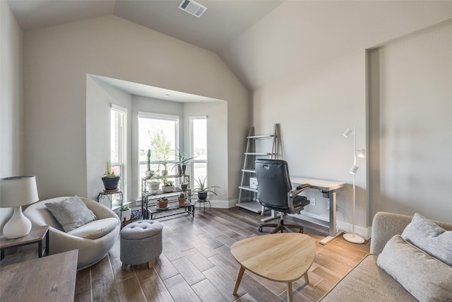 office space featuring lofted ceiling, visible vents, baseboards, and wood finished floors