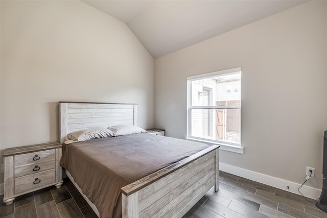 bedroom with lofted ceiling, wood finish floors, and baseboards