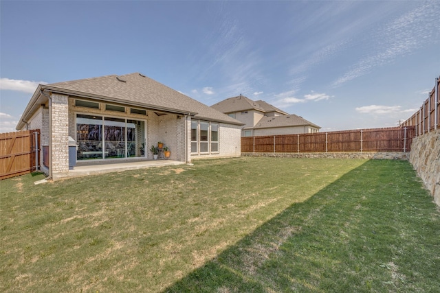 rear view of house featuring a fenced backyard, brick siding, a yard, and a shingled roof