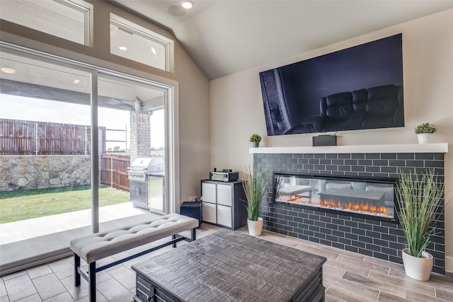 living area with recessed lighting, a glass covered fireplace, and lofted ceiling