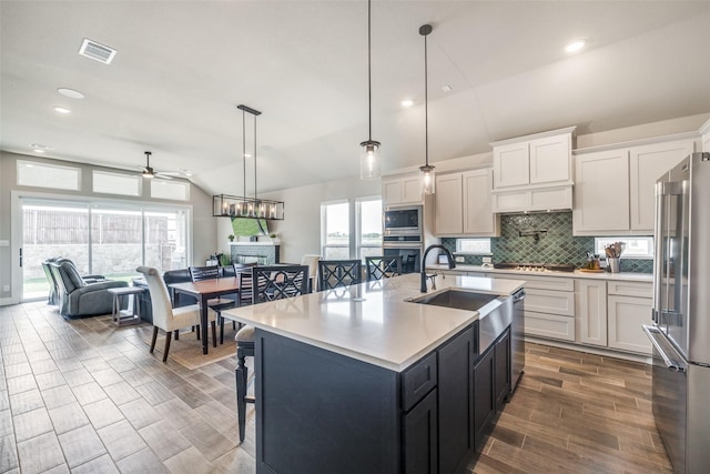 kitchen featuring vaulted ceiling, a sink, decorative backsplash, appliances with stainless steel finishes, and ceiling fan