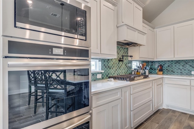 kitchen with white cabinets, light countertops, appliances with stainless steel finishes, and tasteful backsplash