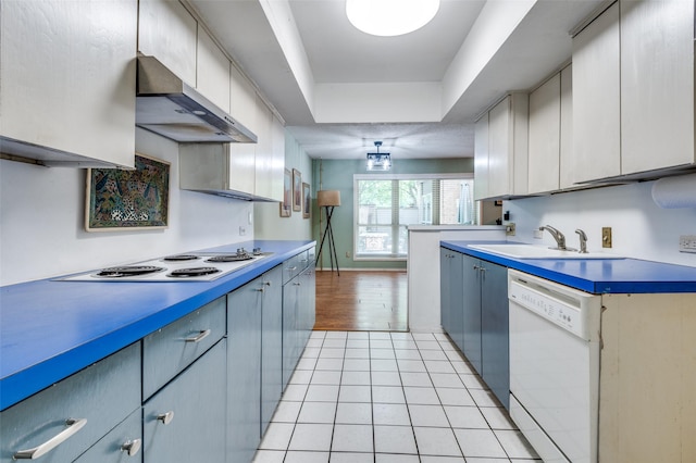 kitchen featuring a sink, white appliances, a raised ceiling, blue cabinetry, and wall chimney exhaust hood