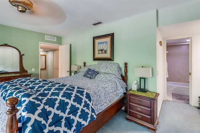 carpeted bedroom with a textured ceiling, visible vents, and ensuite bathroom