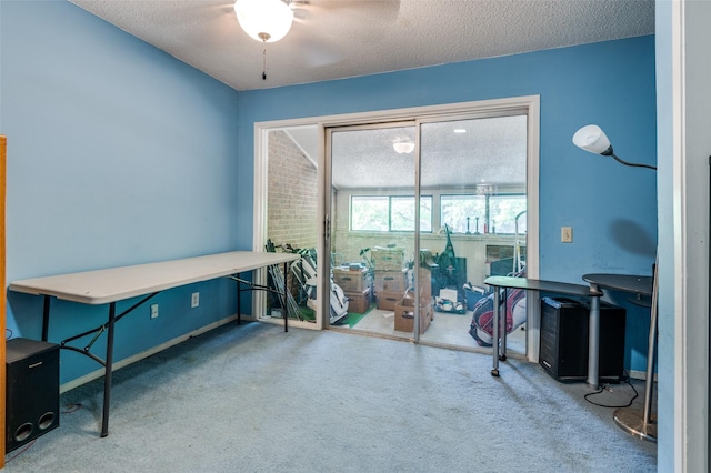 carpeted home office featuring a textured ceiling, a ceiling fan, and baseboards