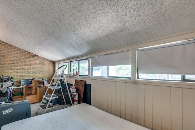 carpeted bedroom featuring brick wall, lofted ceiling, and a textured ceiling