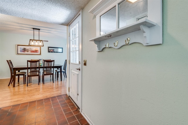 interior space featuring dark tile patterned flooring, baseboards, and a textured ceiling