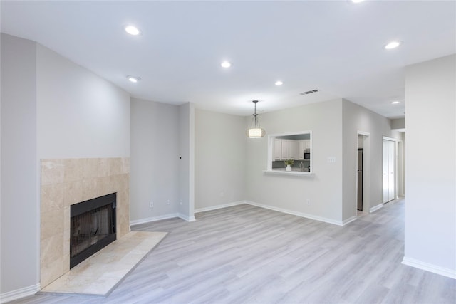 unfurnished living room with recessed lighting, visible vents, a fireplace, and light wood-style floors