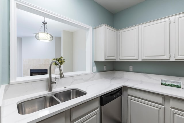 kitchen featuring a sink, dishwasher, pendant lighting, white cabinetry, and light stone countertops
