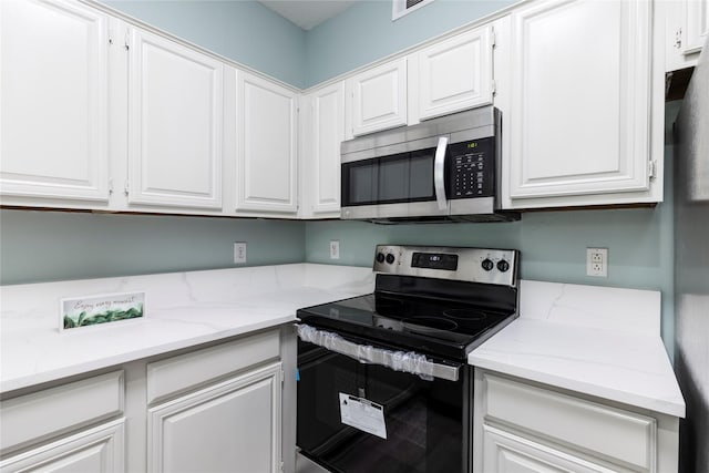 kitchen with white cabinets, stainless steel appliances, and light stone counters