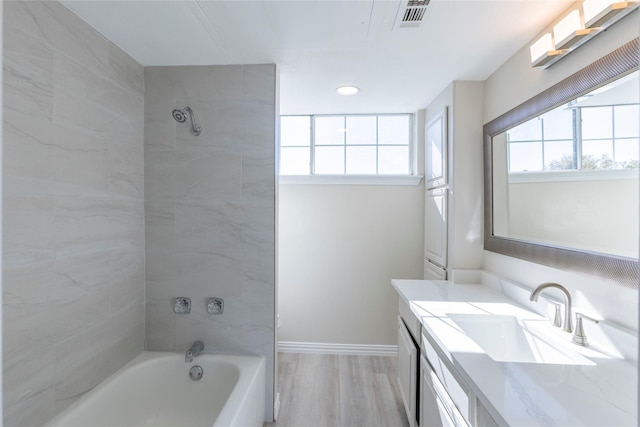 full bath with wood finished floors, visible vents, vanity, baseboards, and shower / tub combination