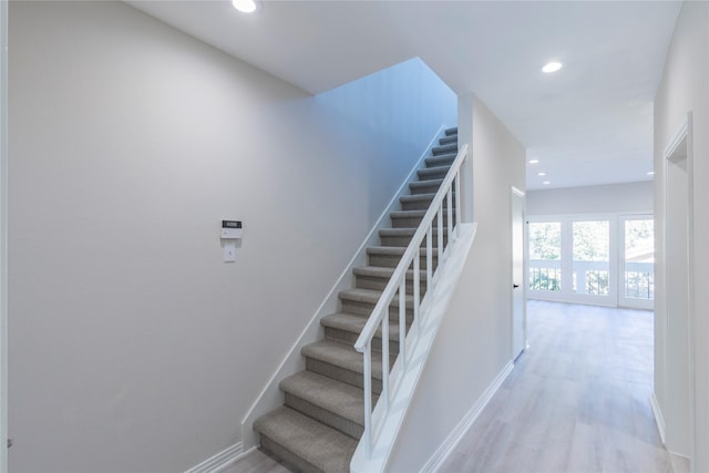 staircase with recessed lighting, wood finished floors, and baseboards