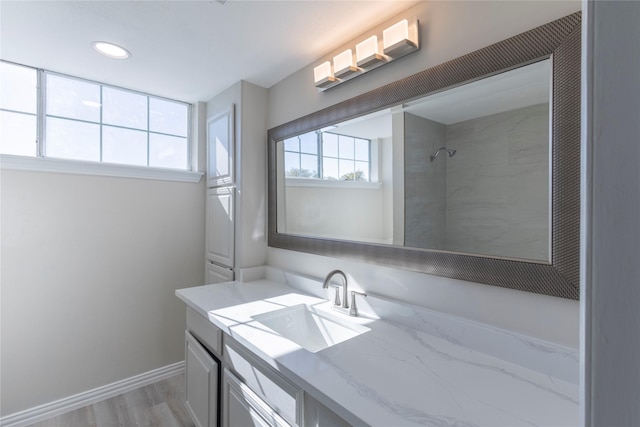 bathroom featuring baseboards, recessed lighting, walk in shower, wood finished floors, and vanity