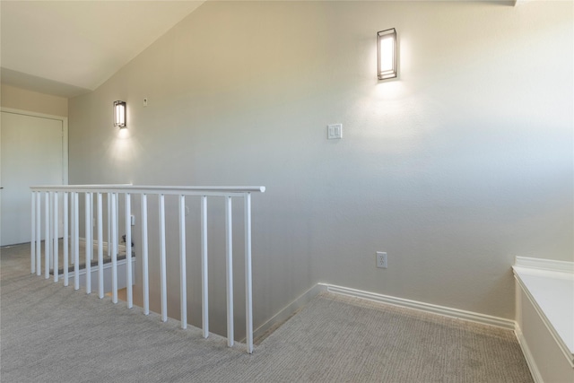 corridor featuring baseboards, carpet flooring, and an upstairs landing