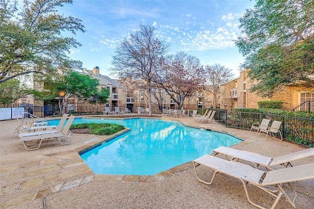 community pool with fence, a patio area, and a residential view