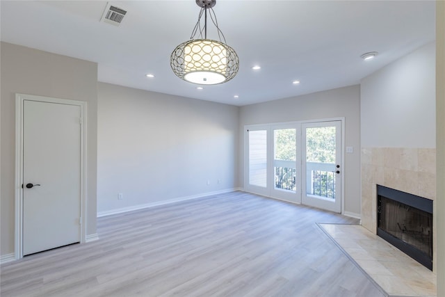 unfurnished living room featuring recessed lighting, a tile fireplace, visible vents, light wood-type flooring, and baseboards