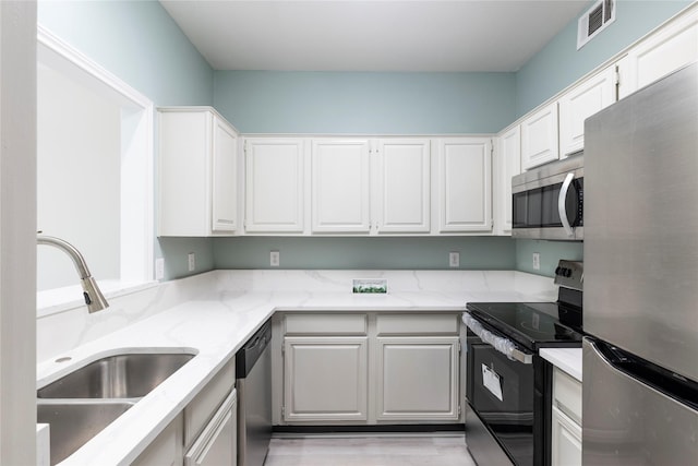 kitchen with white cabinets, a sink, visible vents, light stone counters, and appliances with stainless steel finishes