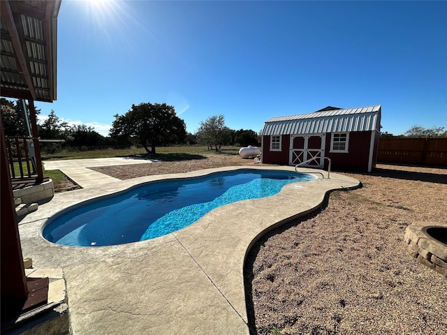 outdoor pool with fence, a patio area, an outdoor structure, and a shed