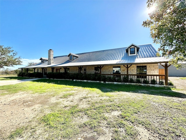 farmhouse inspired home featuring stone siding, a standing seam roof, a front lawn, and metal roof