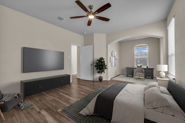 bedroom featuring arched walkways, wood finished floors, and ceiling fan