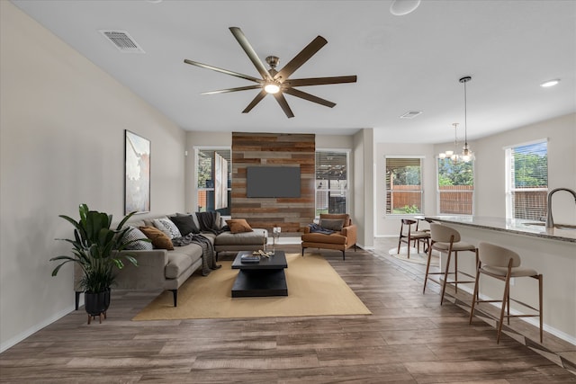 living area with dark wood-style flooring, a ceiling fan, baseboards, a chandelier, and recessed lighting