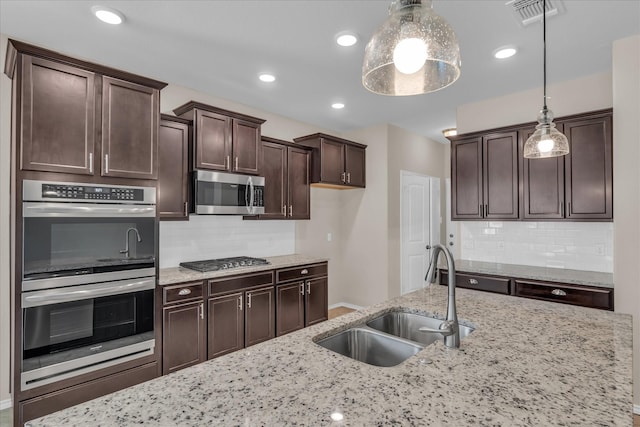 kitchen with stainless steel appliances, a sink, decorative backsplash, dark brown cabinetry, and recessed lighting