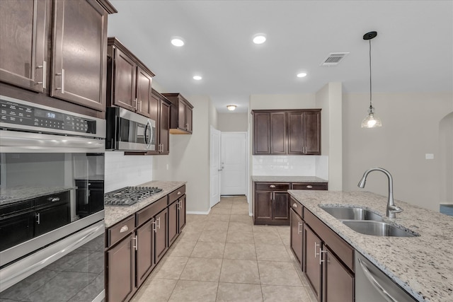 kitchen featuring a sink, appliances with stainless steel finishes, decorative backsplash, light stone countertops, and recessed lighting