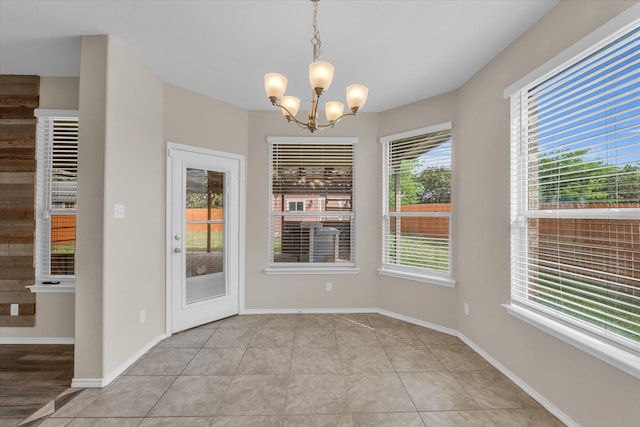 unfurnished dining area with a chandelier, tile patterned flooring, and baseboards