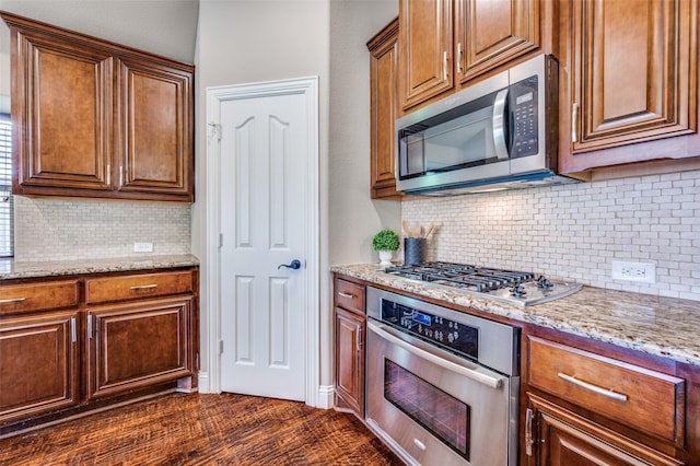 11529 Penick Way, Frisco, TX 75033 - kitchen featuring stainless steel appliances, decorative backsplash, light stone counters, and brown cabinetry