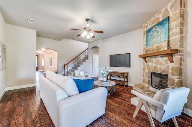 11529 Penick Way, Frisco, TX 75033 - living room featuring arched walkways, stairs, a stone fireplace, and wood finished floors