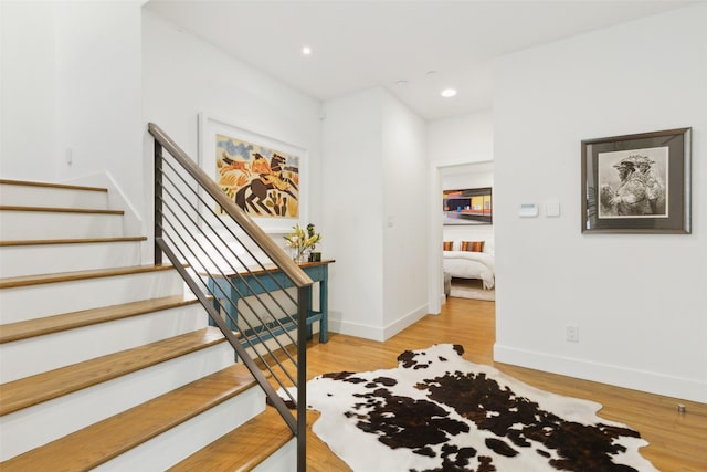 staircase with baseboards, recessed lighting, and wood finished floors