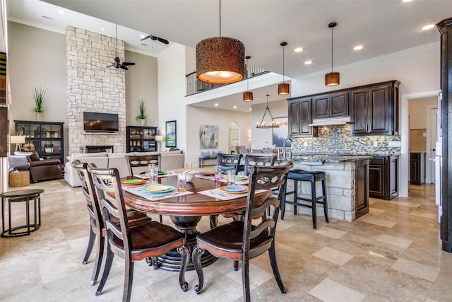 dining room with recessed lighting, a high ceiling, a ceiling fan, ornamental molding, and a fireplace