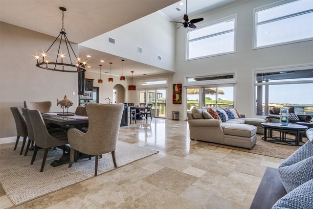 dining space with ceiling fan with notable chandelier, visible vents, and a high ceiling