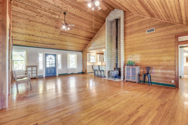 1182 County Road 3025, Bonham, TX 75418 - unfurnished living room with high vaulted ceiling, ceiling fan, a wood stove, wood walls, and visible vents