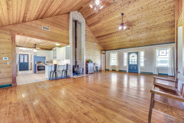 1182 County Road 3025, Bonham, TX 75418 - unfurnished living room featuring wood walls, visible vents, a ceiling fan, wood ceiling, and high vaulted ceiling