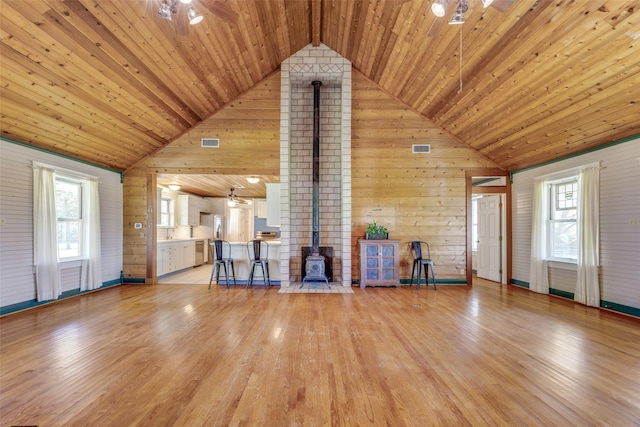 1182 County Road 3025, Bonham, TX 75418 - unfurnished living room with a wood stove, wood walls, wooden ceiling, and ceiling fan