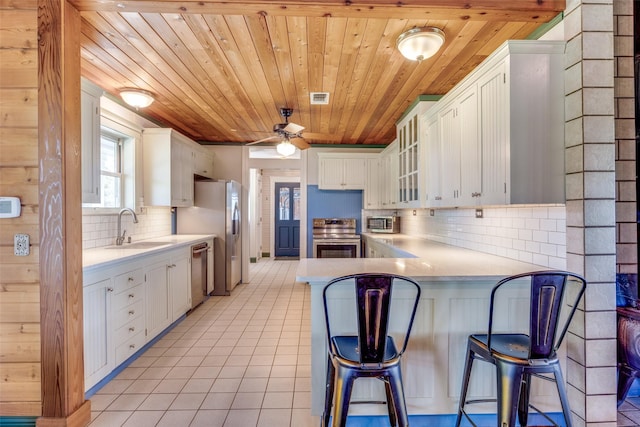 1182 County Road 3025, Bonham, TX 75418 - kitchen with a sink, wood ceiling, backsplash, a peninsula, and appliances with stainless steel finishes