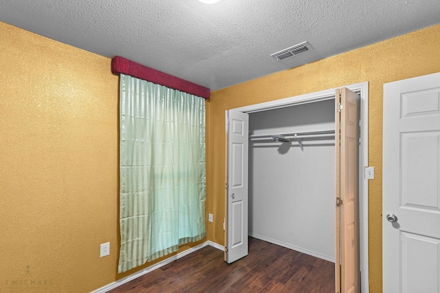 5663 Bretwood Dr, Keithville, LA 71047 - unfurnished bedroom featuring a textured ceiling, dark wood finished floors, visible vents, a closet, and a textured wall
