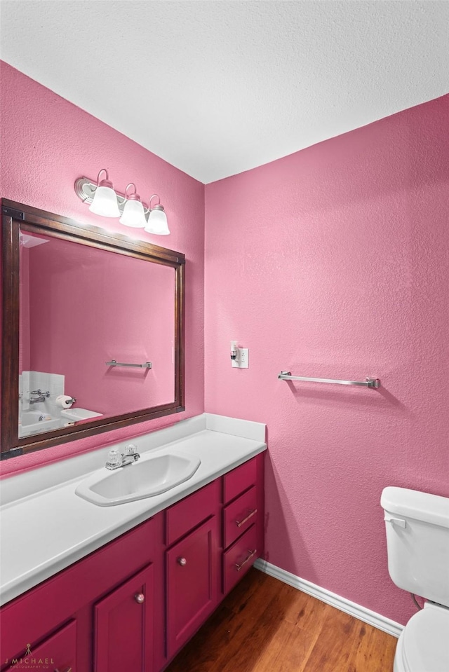 5663 Bretwood Dr, Keithville, LA 71047 - bathroom with toilet, baseboards, wood finished floors, a textured wall, and vanity