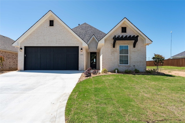 view of front facade with a garage, brick siding, a front yard, and concrete driveway