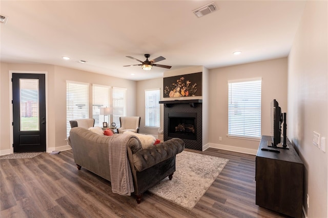 living room featuring baseboards, dark wood-type flooring, visible vents, and a fireplace