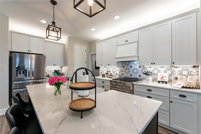 kitchen with tasteful backsplash, pendant lighting, stainless steel appliances, custom range hood, and light stone countertops